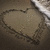 A heart-shaped icon with a textured, muted brown and gray color palette, featuring a subtle gradient and pixelated edges against a dark background.