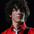 A four- shows a person with curly dark hair in different outfits and backgrounds, including red jacket on black background, light shirt on brown patterned background, and gray vest over blue shirt on light blue background