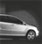 A grayscale image of a car in motion, viewed from the side with visible wheels and windows against a dark background.