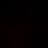 A dark, nearly black image with faint repeating text patterns visible in the background.