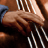 A pixelated close-up of a hand holding multiple thin white strings against a brown background with dark and light brown tones.