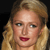 Pixelated close-up of a person with light brown hair, fair skin, and red lips against a dark background.