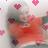 Pixelated static image with blurred human figure in red tones, surrounded by pink heart shapes on light background.
