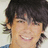 A pixelated image of a person with dark hair and light skin smiling, next to red digital text on black background.