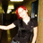 A pixelated figure with red hair wears a black top and white collar, extending an arm toward the left side of the frame.