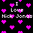 Black background with scattered pink pixelated hearts and repeated white text reading "I Love Nick Jonas" in a retro digital style.