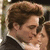 A close-up of a man with brown hair and a woman in profile, both wearing dark formal attire against a blurred background.