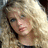 Pixelated image of a person with long blonde hair and blue eyes, accompanied by blue pixelated text on a light background.