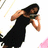 A woman in a black dress holds a dark object near her face, with background elements shifting between white and pink sections.