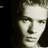 Static grayscale pixelated portrait of a person's face with high contrast and dithering, displayed on a dark background.