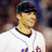 A baseball player in a white uniform with blue and red accents smiles while wearing a dark cap, with text overlaid on one view.