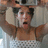 A pixelated image of a person holding a camera above their head with arms raised, wearing a white sleeveless top with a patterned design, accompanied by pixelated text reading "yeah" and "that's me!".