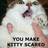 A pixelated image of a white cat with pink ears and nose, a human hand touching its nose, and partially legible text below.