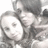 Pixelated grayscale image of two figures in close physical proximity, one figure's face partially visible with a neutral expression, the other figure's face obscured by the first figure's head.