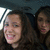 Two women with long brown hair sit inside a vehicle, one smiling broadly while the other's expression shifts slightly across frames.