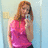A pixelated image of a person with long brown hair wearing a pink sleeveless top and dark pants, standing against a light blue background.