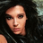 Pixelated close-up of a person with dark curly hair and light skin, wearing a black sleeveless top against a blurred background.