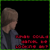 A four- shows a person with short blonde hair in a blue jacket and black shirt observing another person in a dark shirt and green pants, with red and white text overlays