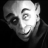 Pixelated grayscale image of a bald human face with a neutral expression, dark eye, and visible eyebrow, set against a solid black background.