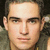 A static image of a person with short dark hair wearing a gray sleeveless top, displayed in a with three visible sections