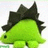 Green dinosaur with black spikes on its back stands against a white background, next to pink pixelated text on black.