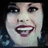 Pixelated close-up of a person with dark hair and red lipstick smiling, next to yellow pixelated text on black background.