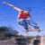 A person in a red shirt and blue jeans performs a skateboarding trick against a clear blue sky background.