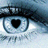Pixelated close-up of a stylized eye with a black heart-shaped pupil, set against a blue-toned background with blurred horizontal elements.