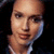 Pixelated close-up of a person's face with light skin tone, dark hair, and a neutral expression against a dark background.