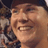 Pixelated close-up of a person's face with visible teeth and partial hair, set against an indistinct background.