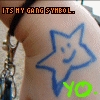 A close-up of a person's arm with a blue star-shaped tattoo featuring a smiley face, overlaid with pixelated text reading 'ITS MY GANG SYMBOL.'