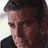 Pixelated close-up of a person's face with dark hair and light skin, wearing a dark shirt against a bright background.