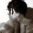 Pixelated grayscale image of a person with dark hair and glasses, partially obscured by text overlays on white and black backgrounds.