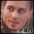 Pixelated close-up of a person's face with light skin tone, brown eyes, and neutral expression; black text 'fan' at bottom right.
