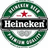 Circular green wreath with white floral patterns encircles a central red star above a black banner reading 'Heineken' in white text.