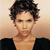 Pixelated image of a person with short dark curly hair wearing a black top against a light brown gradient background.