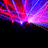 Pixelated abstract animation with shifting red, purple, and blue light beams radiating from a central bright spot against black background.