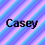 Pixelated text 'Casey Casey' in black serif font on a chevron-patterned background of blue and pink stripes.