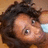 Static pixelated image of a person with dark curly hair and light skin, showing a partial face with one eye visible and a blurred background.