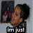A pixelated image of a person with dark hair in a bun, wearing a blue top, with a background featuring a framed picture of a person in red clothing.