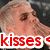 Pixelated close-up of a person's face with light brown hair and visible skin texture, overlaid by red text reading 'kisses' on white background.