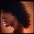 Animated sequence showing a person with dark curly hair transitioning from covering their face to smiling, accompanied by a light beam and stylized text on an orange background.