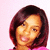 Pixelated portrait of a person with shoulder-length dark brown hair, light skin tone, and pink clothing against a pale pink background.