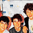 Three pixelated figures with dark hair and orange-toned skin stand in a row against a light background with blue and yellow accents.