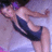 Pixelated image of a person in a dark blue swimsuit with white stripes, lying on a light purple background.