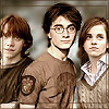 Three people stand side-by-side in a pixelated image with brown and beige tones, the central figure wearing a brown sweater with a patch on the left sleeve.