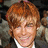 A pixelated image of a person with reddish-brown hair and a white-collared shirt on a red background with pink text.
