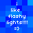 Blue pixelated background with white text reading 'i like flashy lights!!!!' and '=}' repeated in a pattern