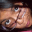 Pixelated close-up of a person's face with light skin, dark hair, and large eyes showing visible eyelashes.