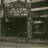 Pixelated grayscale image of a dark rectangular shape with lighter rectangular elements above and to the right, set against a gradient background.